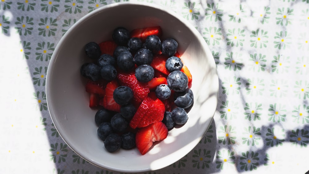 a bowl of berries and strawberries on a table