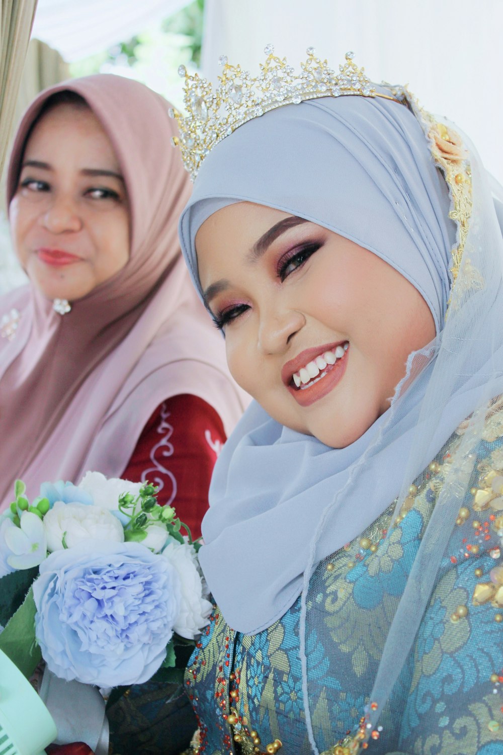 a woman in a hijab holding a bouquet of flowers