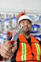 a man in an orange vest holding a wrench