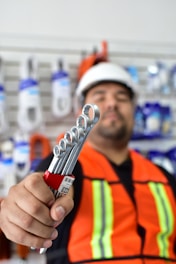 a man in an orange vest holding a wrench