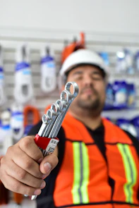 a man in an orange vest holding a wrench