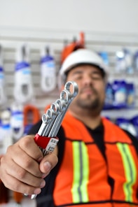a man in an orange vest holding a wrench