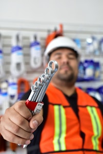 a man in an orange vest holding a wrench