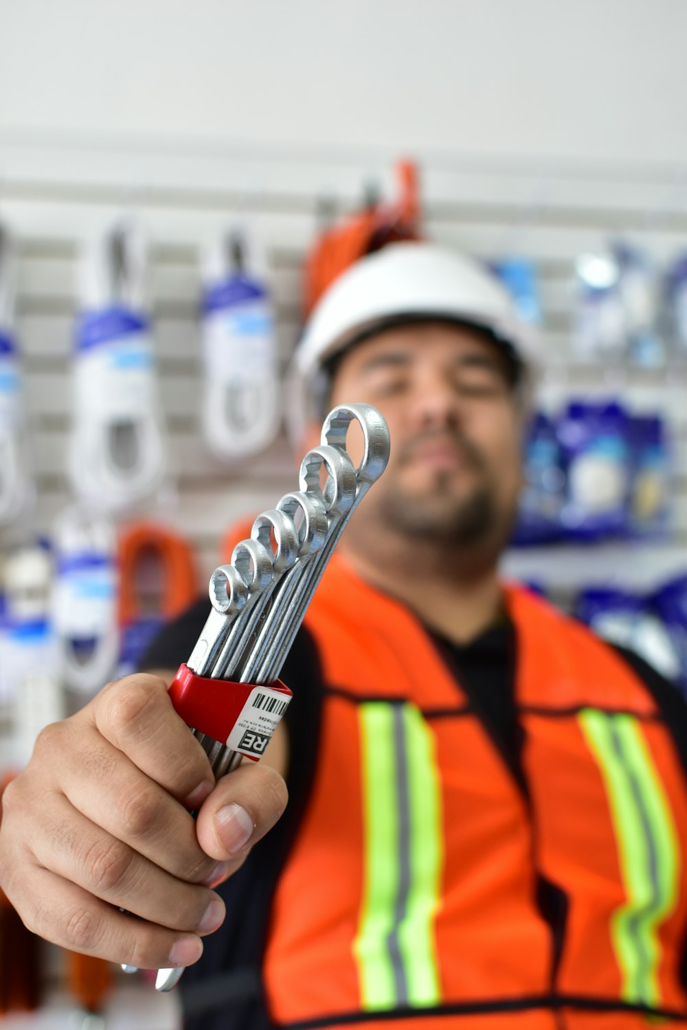 a man in an orange vest holding a wrench