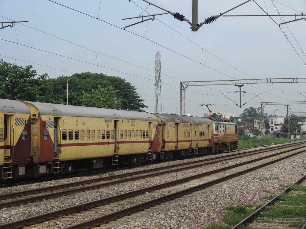 a yellow train traveling down train tracks next to a forest