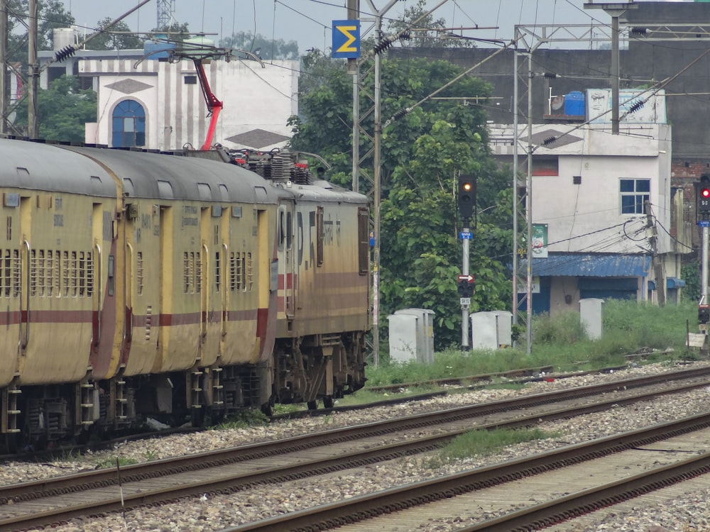 a yellow train traveling down train tracks next to a forest