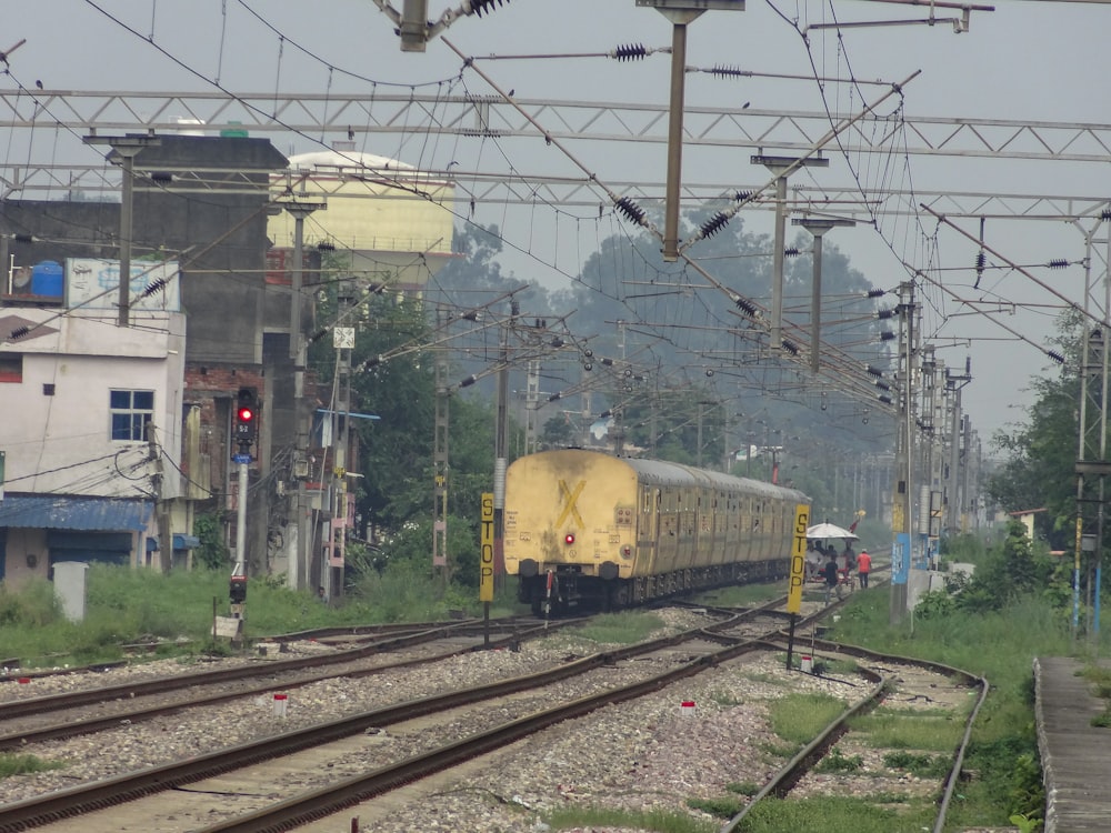 a yellow train traveling down train tracks next to tall buildings