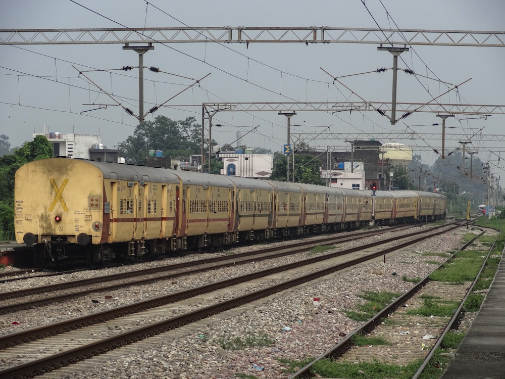 a yellow train traveling down train tracks next to a forest