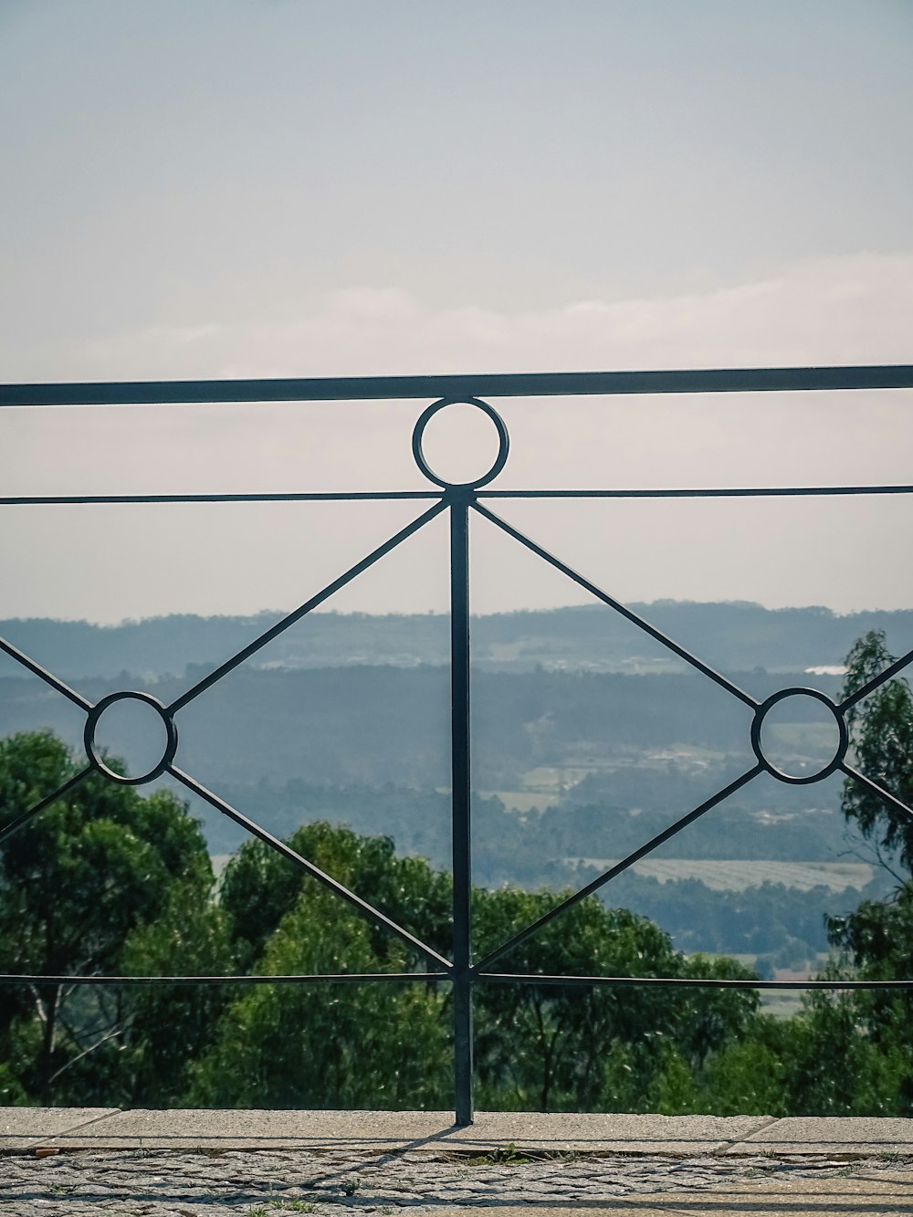 a metal fence with a view of a valley in the distance