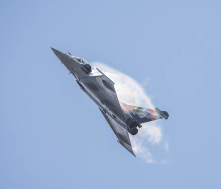 a fighter jet flying through a blue sky