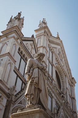 a statue of a man holding a book in front of a building