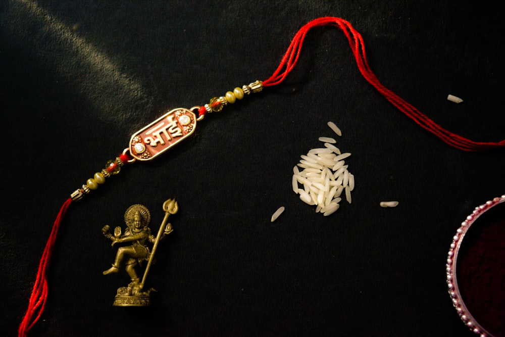 a red string with beads and a statue on a black surface