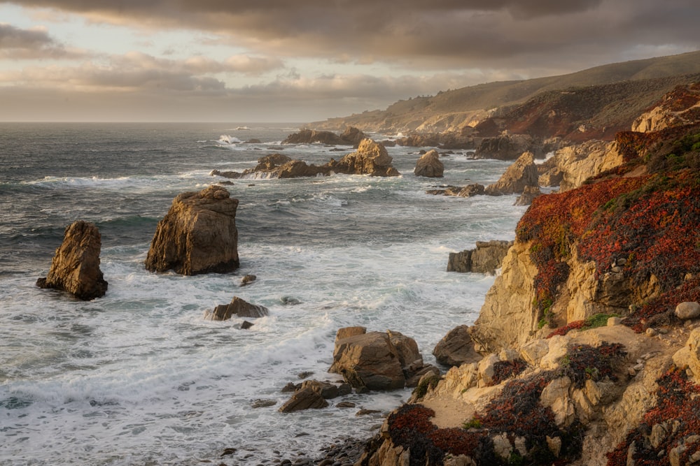 a view of the ocean with rocks and a cloudy sky