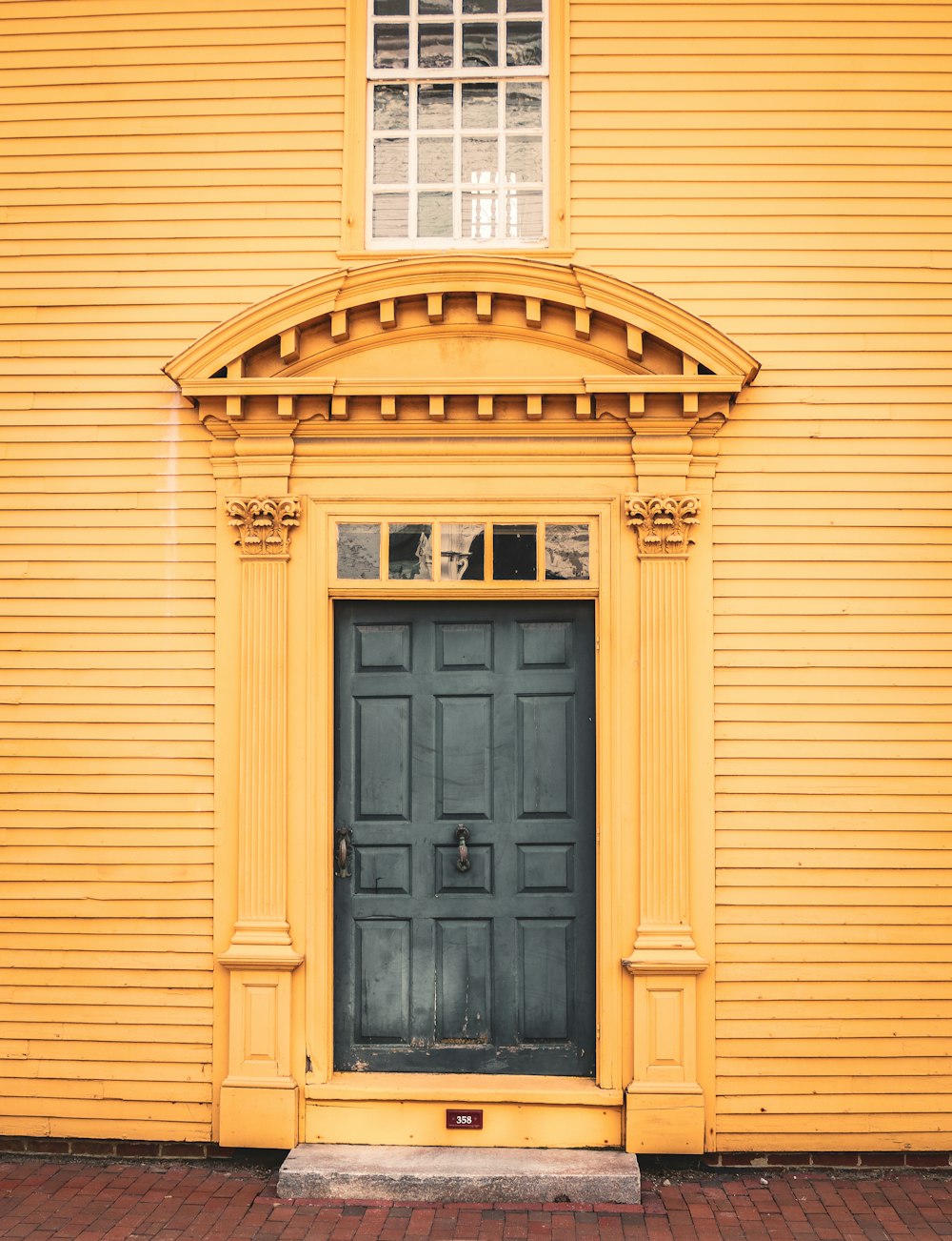 a yellow building with a black door and window
