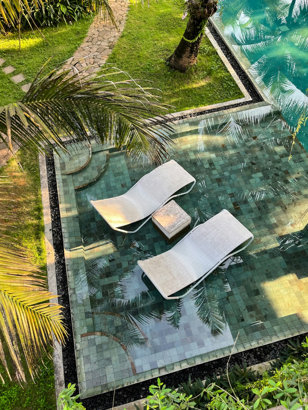 a couple of lounge chairs sitting on top of a tiled pool