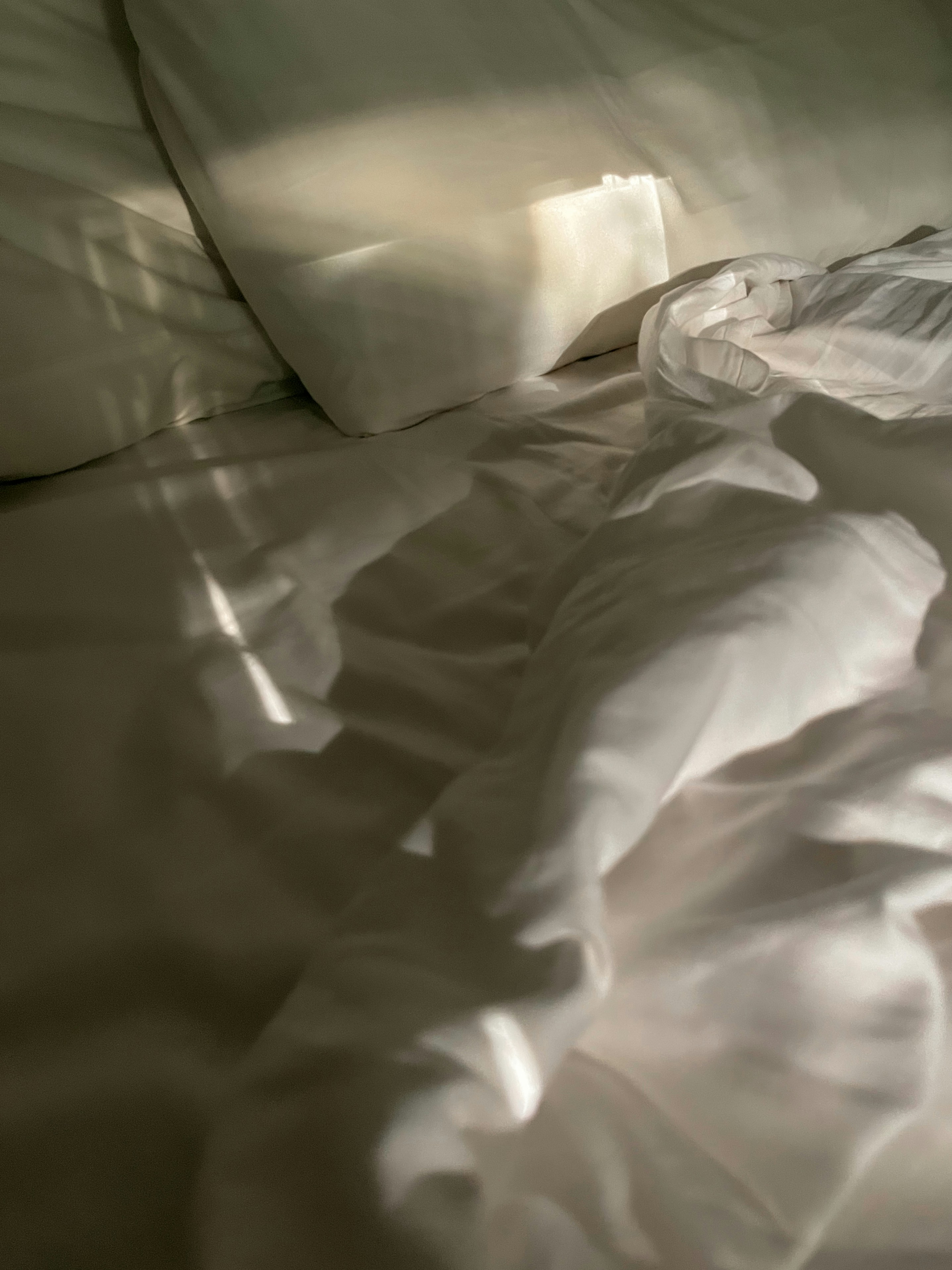 an unmade bed with white sheets and pillows