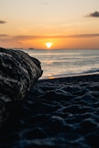 A serene Fijian beach at sunset with a camera resting on driftwood nearby.