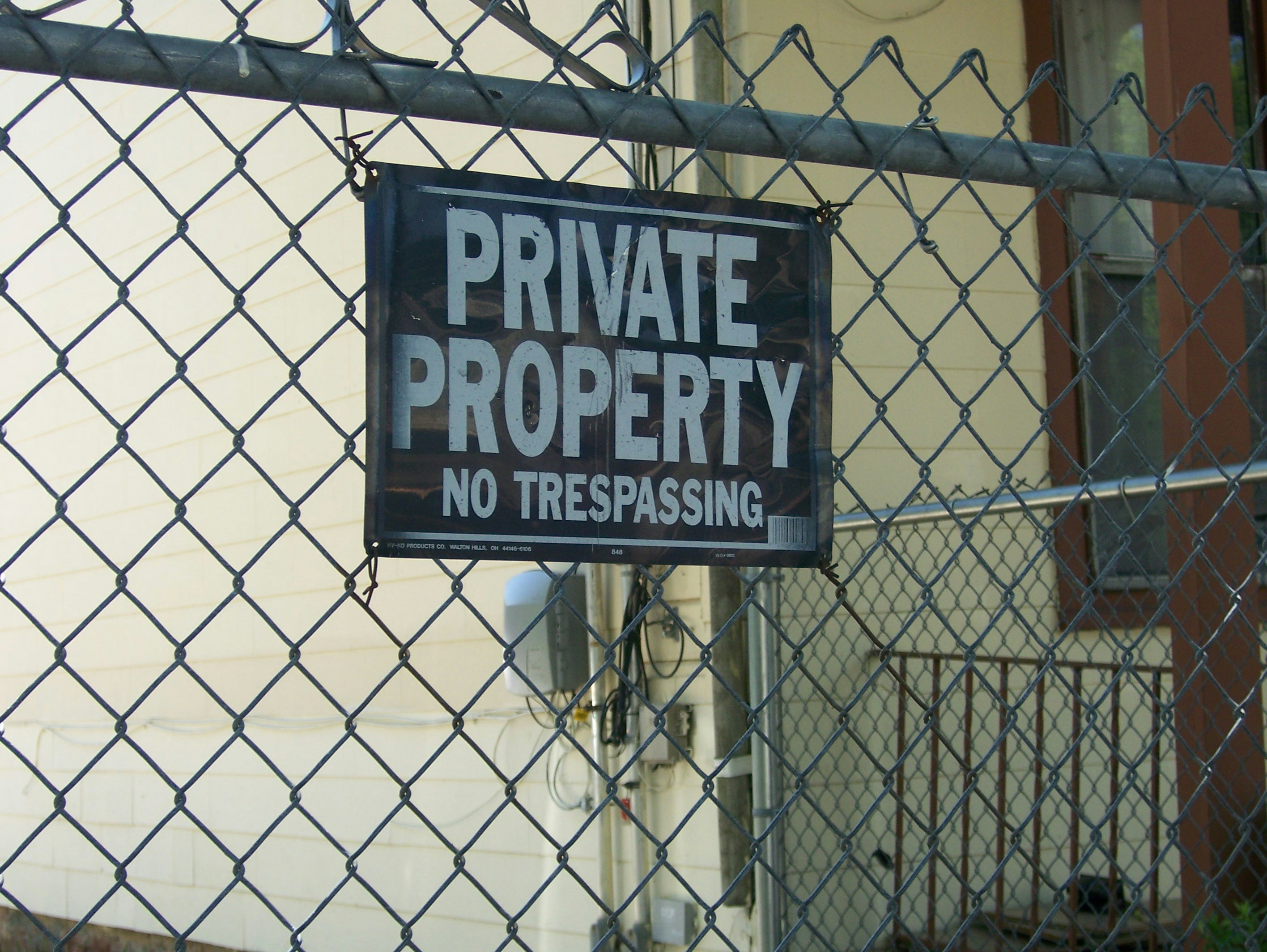 a private property sign hanging on a chain link fence
