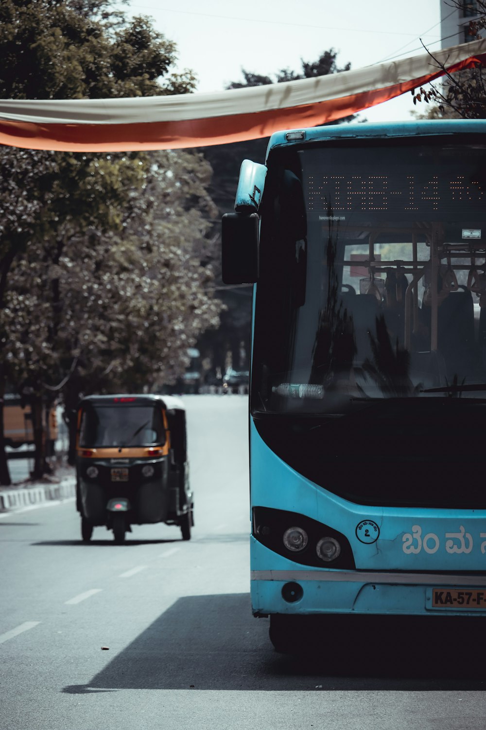 a blue bus driving down a street next to a tall building