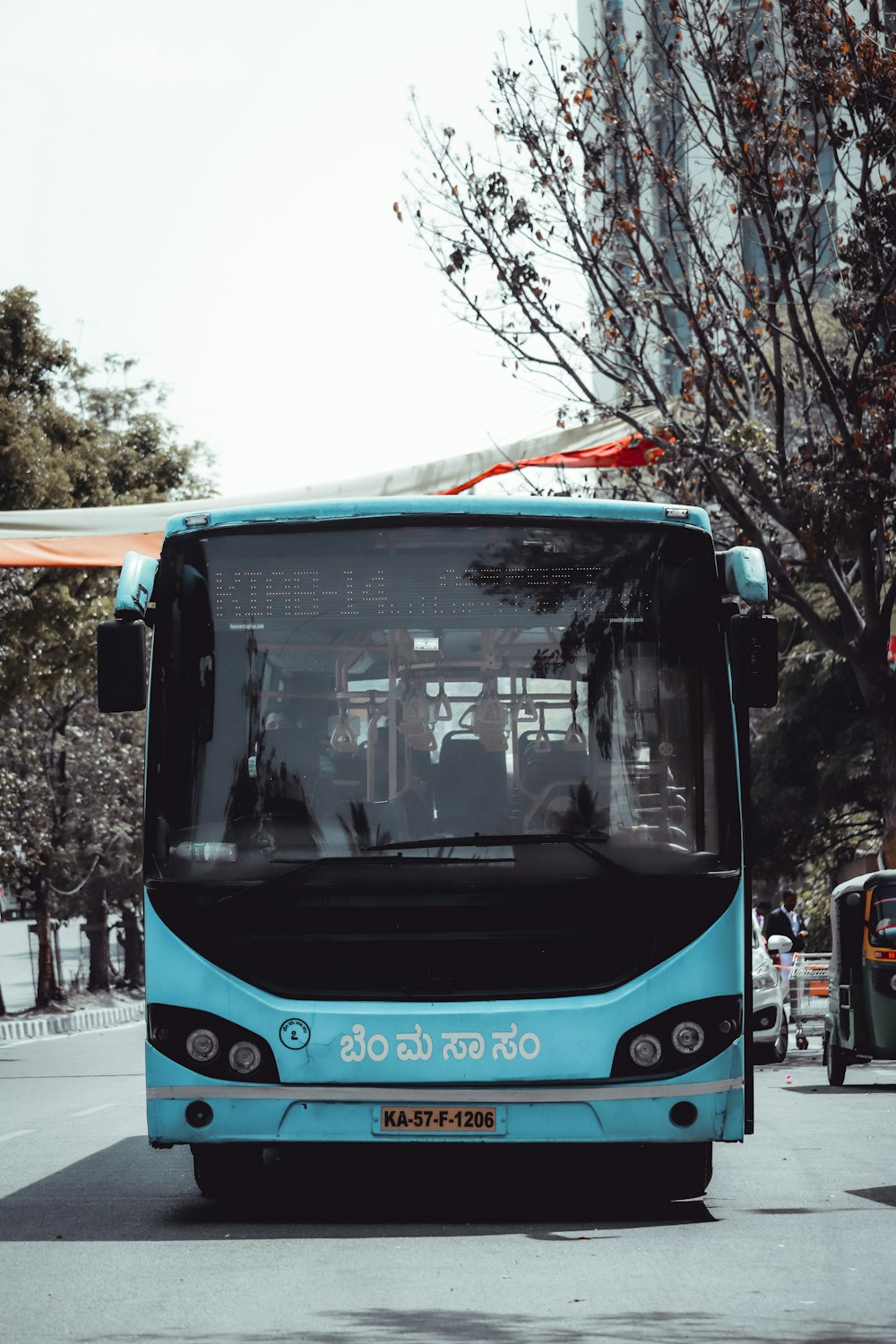 a blue bus driving down a street next to a tall building