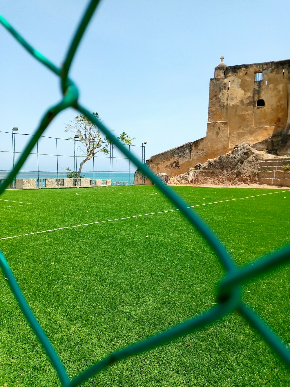 a soccer field behind a fence with a view of the ocean