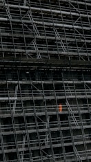 A modern sustainable building under construction with orange safety equipment visible.