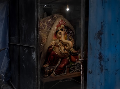 A serene wooden murti of Lord Ganesha placed on a rustic earthen shelf with soft natural light.