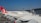 Several Turkish Airlines planes are parked at an airport, with a focus on the aircraft's wings and tailfins showing the airline's logo. The airport terminal and control tower are visible in the background under a clear blue sky.