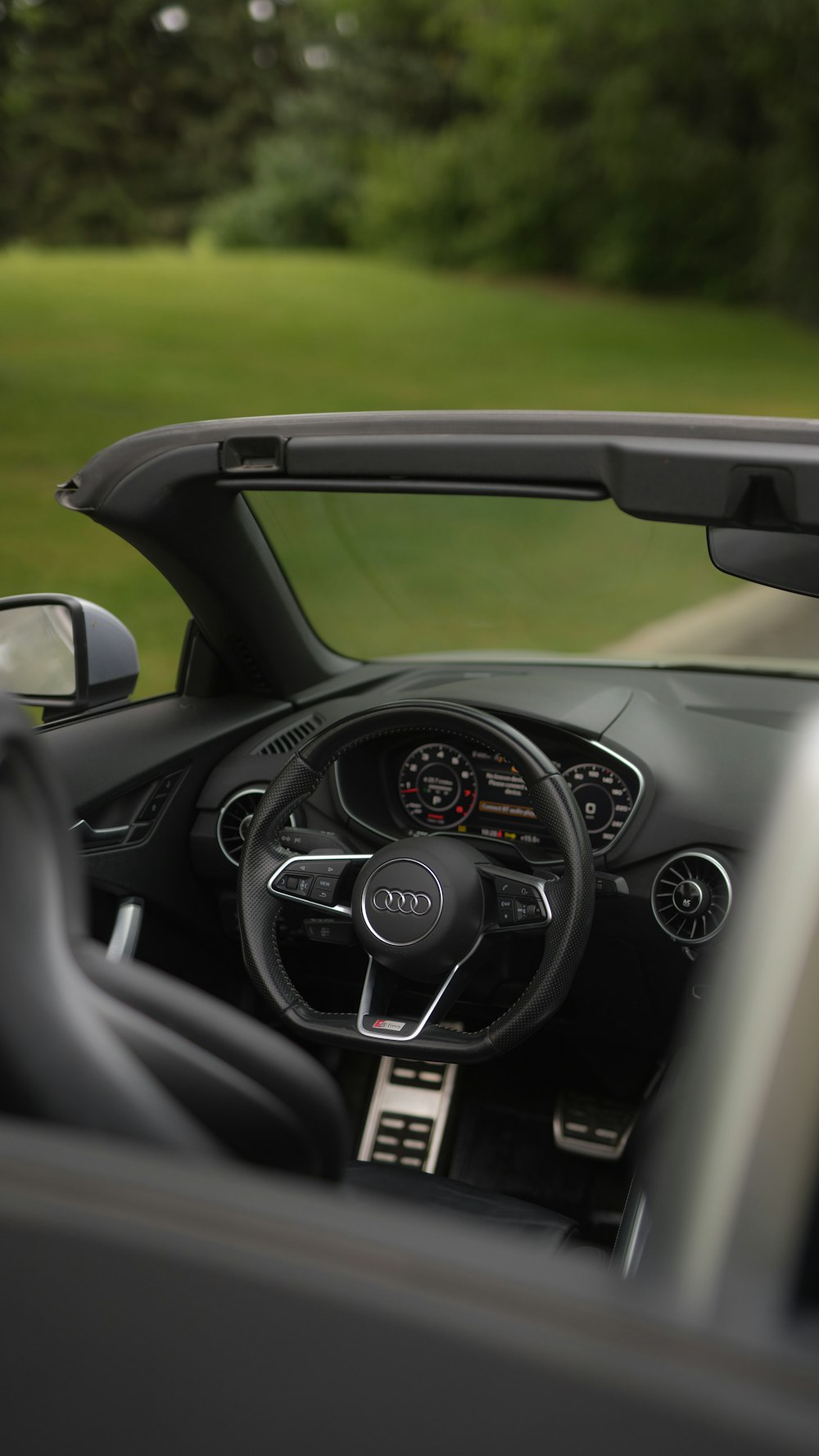 a car driving down a country road next to a lush green field