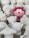 A group of sculpted figurines are gathered together, mostly in white with one prominent red and pink figure standing out. The figures appear to be cartoonish characters with varying shapes, including round and animal-like forms. They are intricately designed with different facial expressions and accessories.