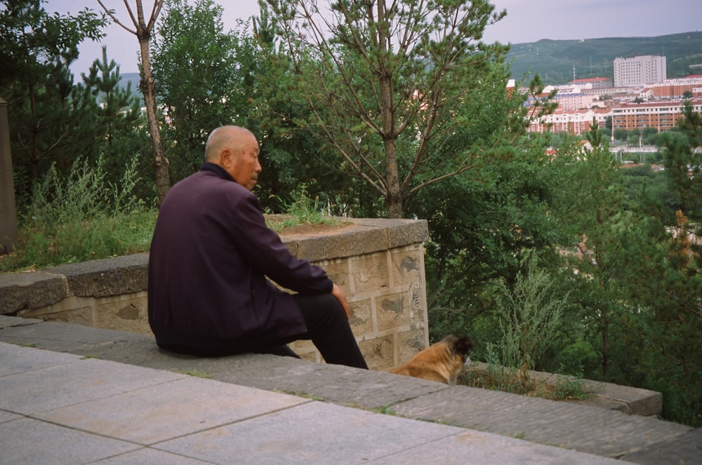 a man sitting on a ledge next to a dog