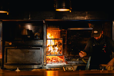 Chef focused on baking pizza in a traditional stone oven with glowing flames.