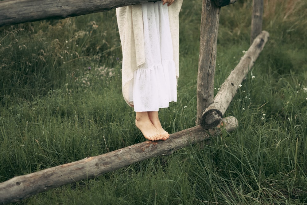 a woman in a white dress standing on a wooden fence