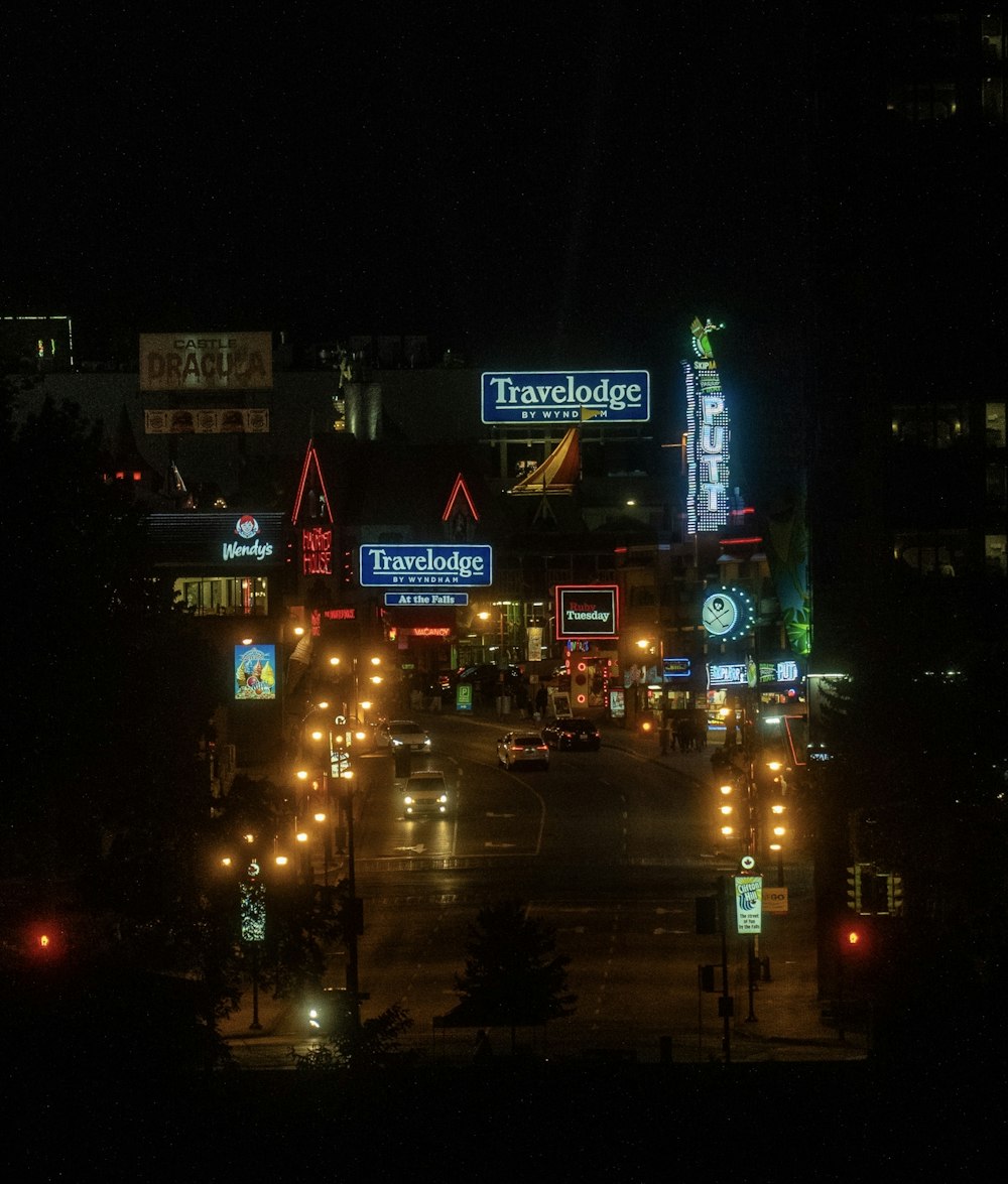 a city street at night with a lot of signs lit up