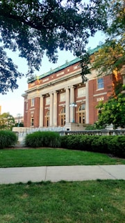 a large brick building with columns and a green roof
