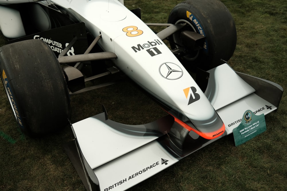 a white race car sitting on top of a lush green field