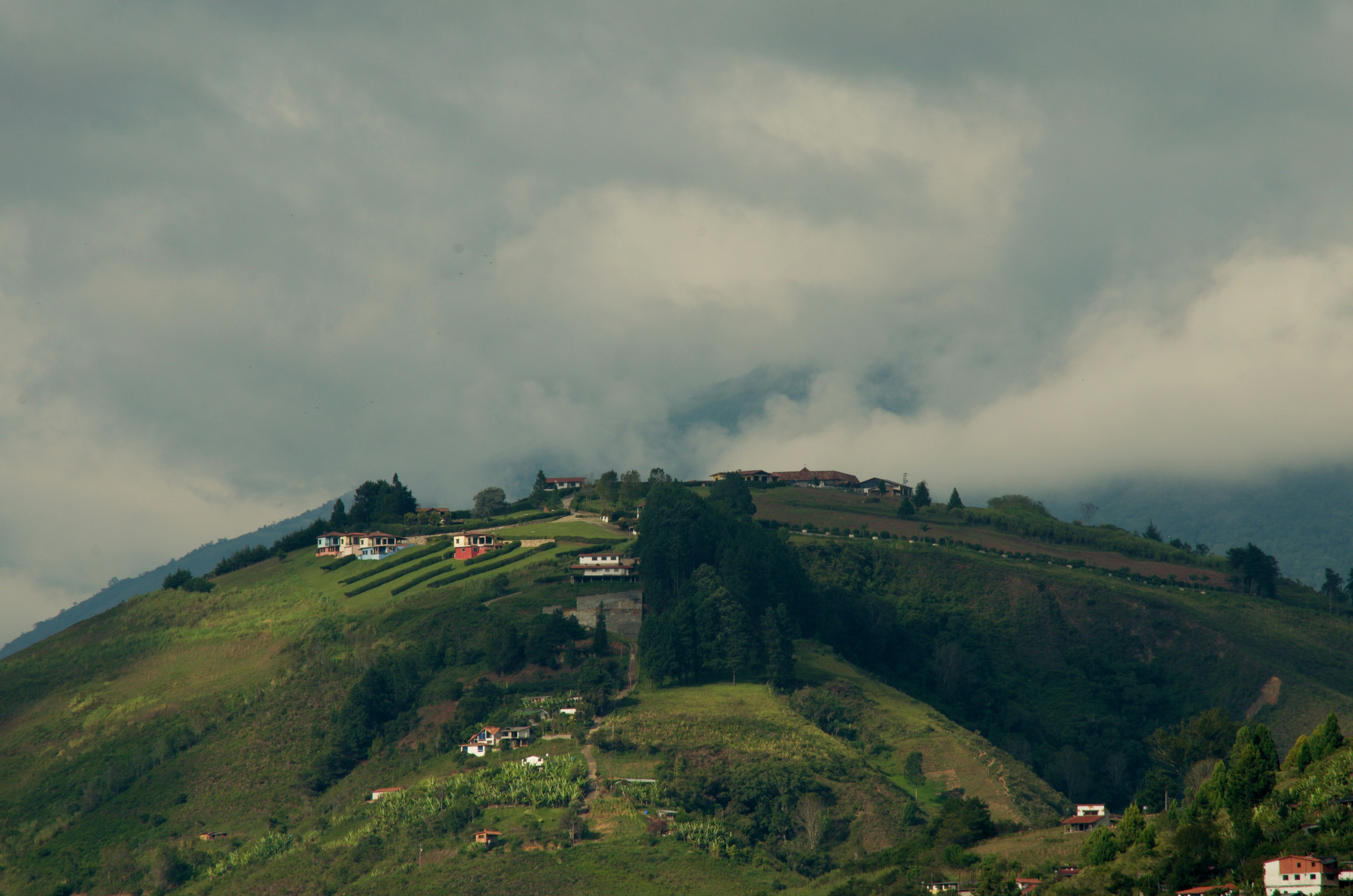 a lush green hillside covered in lots of clouds, 