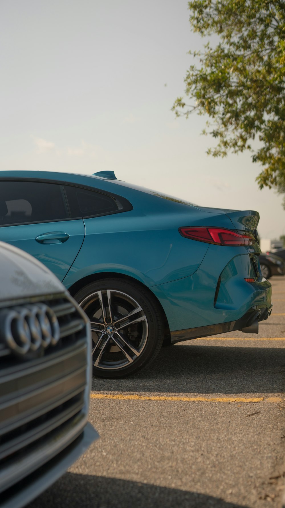 a blue car parked in a parking lot next to a tree