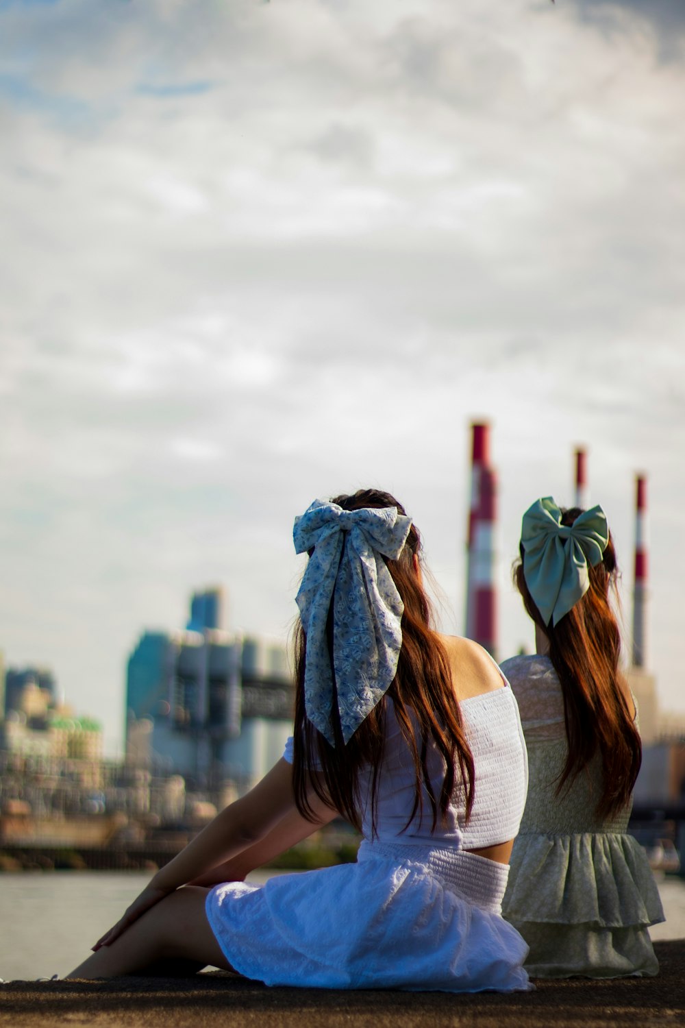 two women sitting on a ledge looking at the city