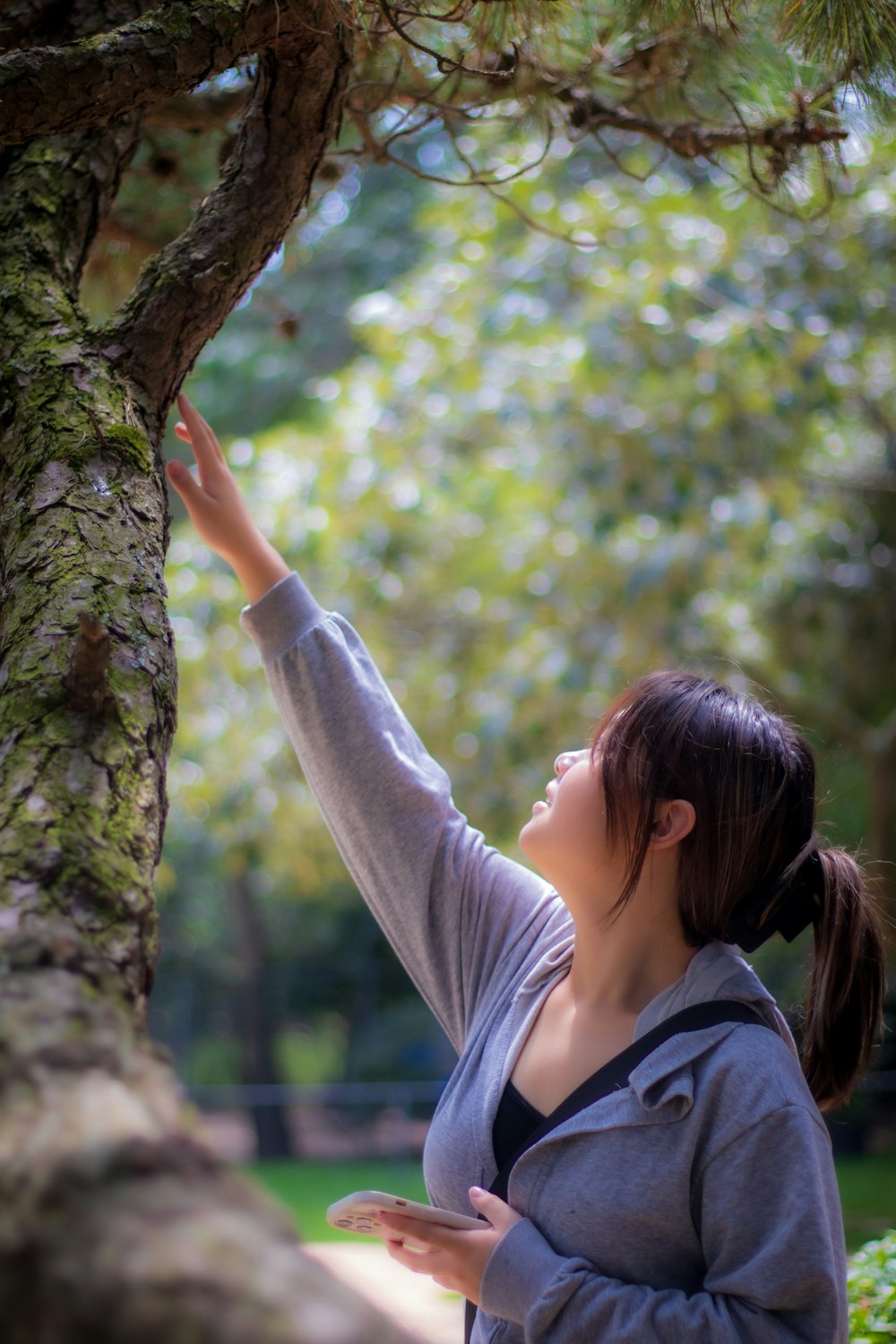 a woman is reaching up to a tree