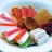 A plate filled with a colorful assortment of sweets, including sugar-coated jelly candies in various shapes and colors and a small cream-filled pastry in the center. The candies are arranged in an aesthetically pleasing manner, with bright hues of pink, orange, red, and green.