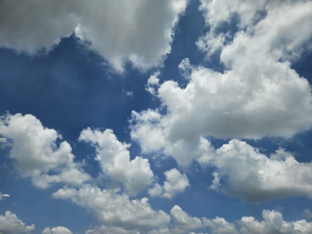 a plane flying through a cloudy blue sky