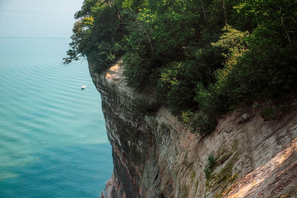 a boat floating on the water near a cliff
