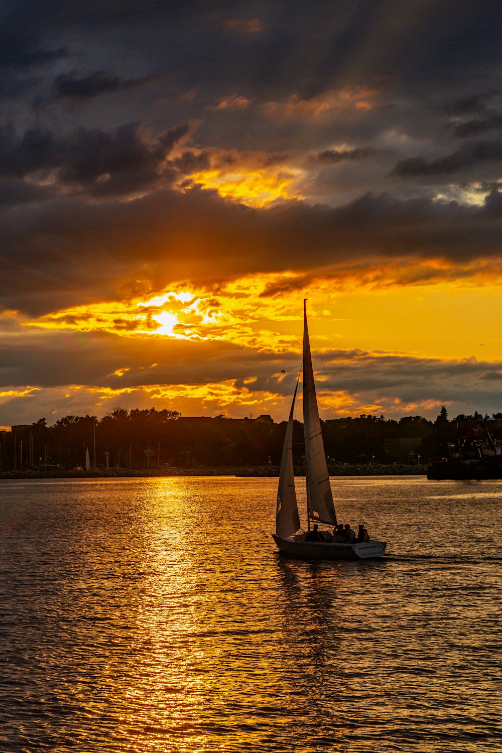 ein Segelboot im Wasser mit einem Sonnenuntergang im Hintergrund