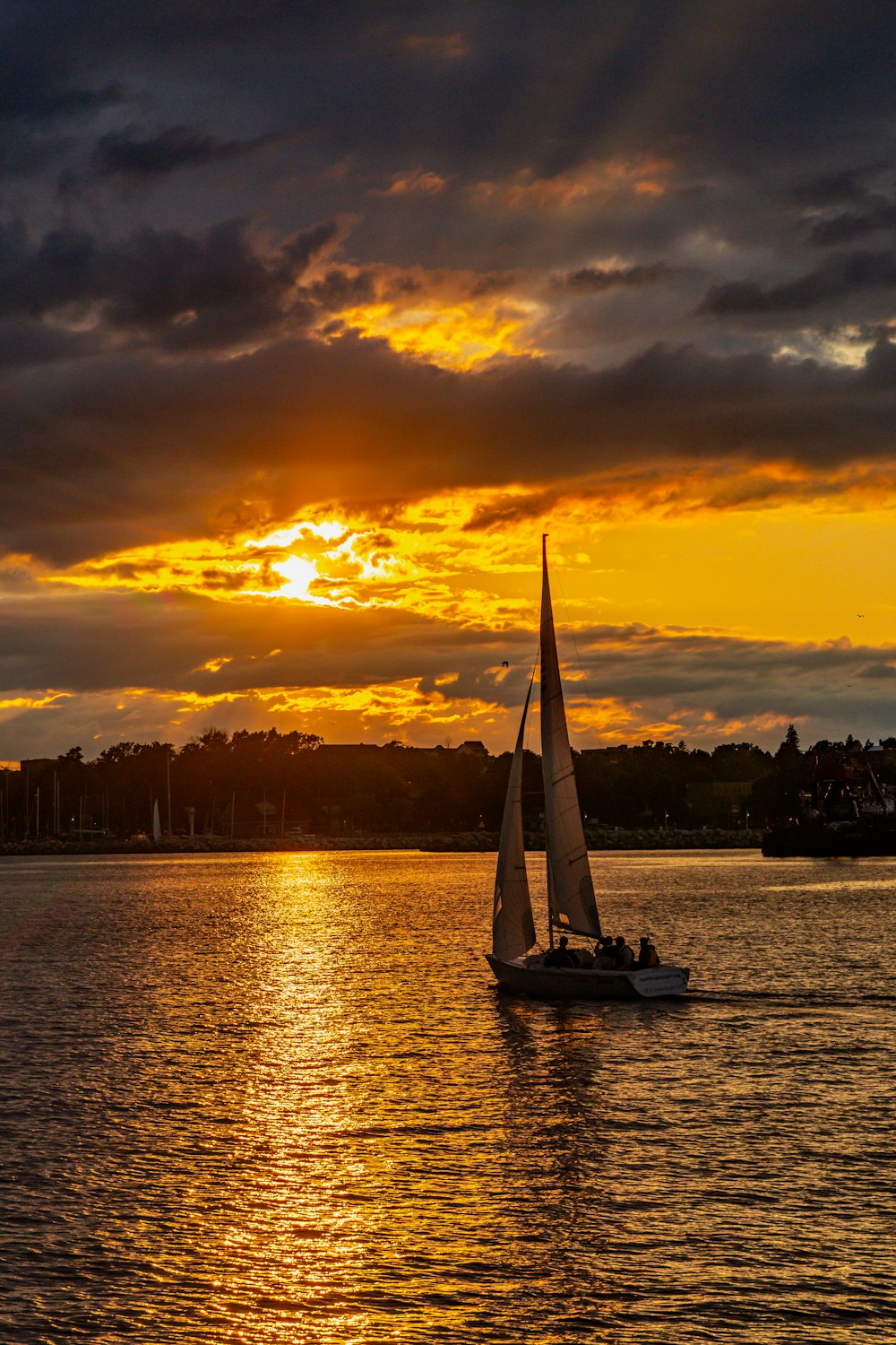 a sailboat in the water with a sunset in the background