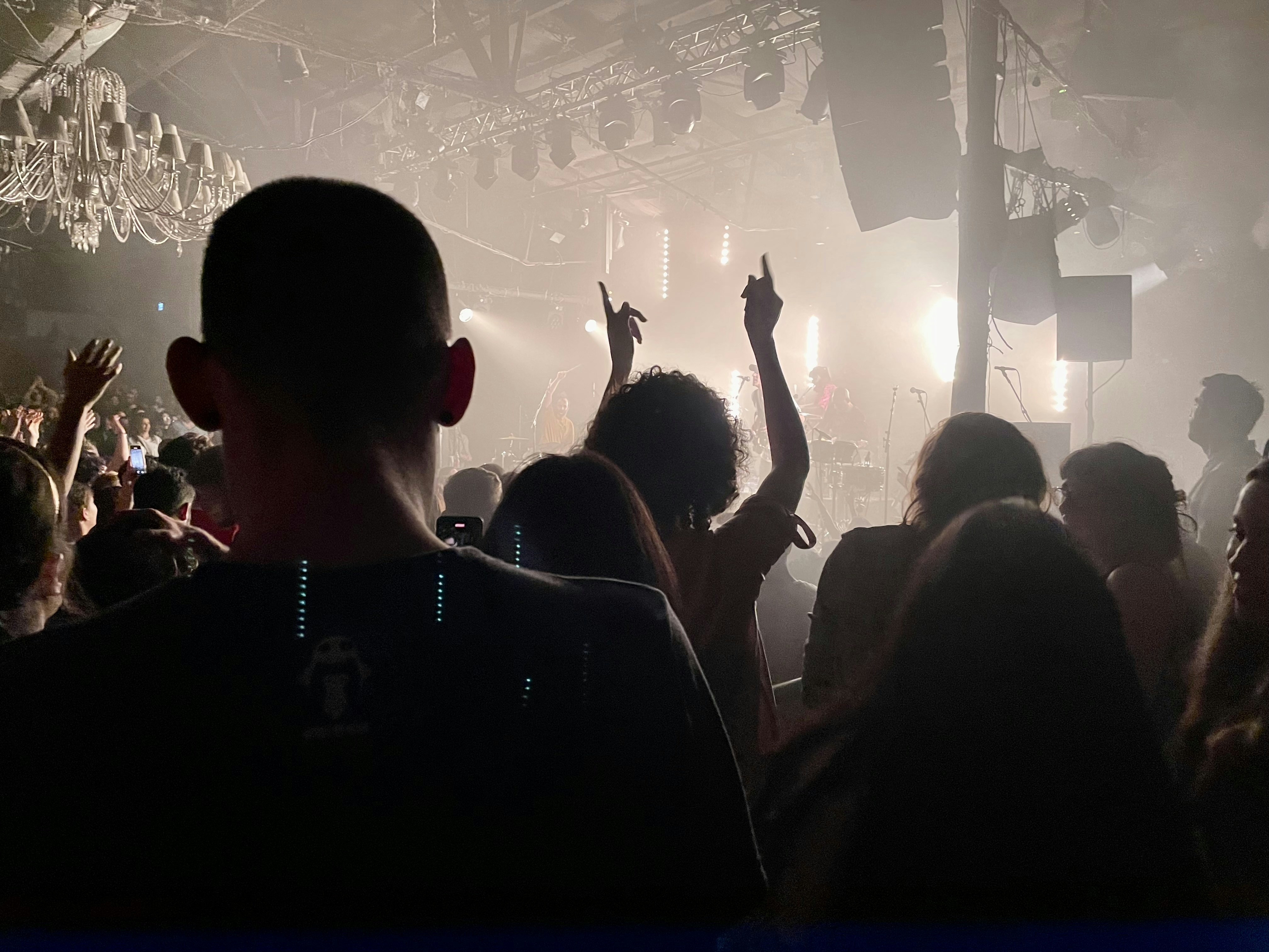 Concert crowd with raised hands under stage spotlights