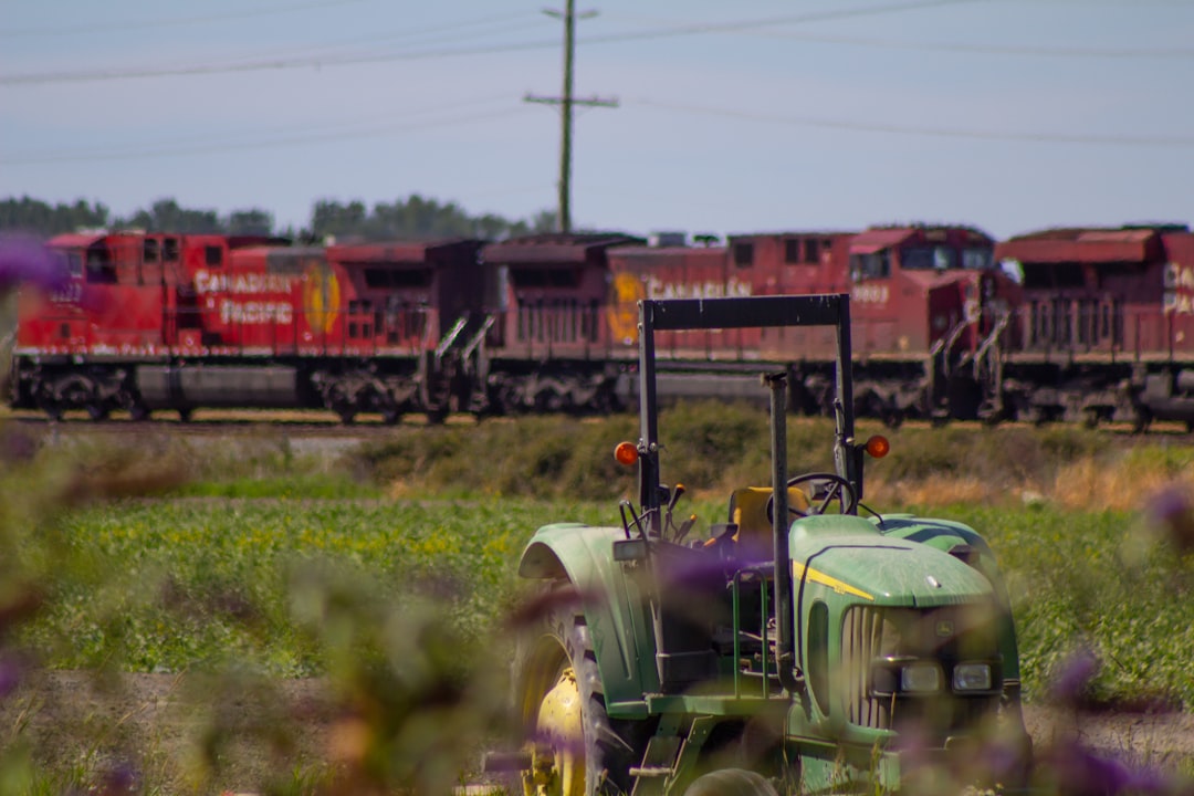 a tractor is parked in a field with a train in the background,