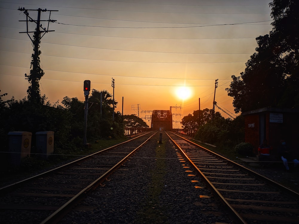 a train track with the sun setting in the background