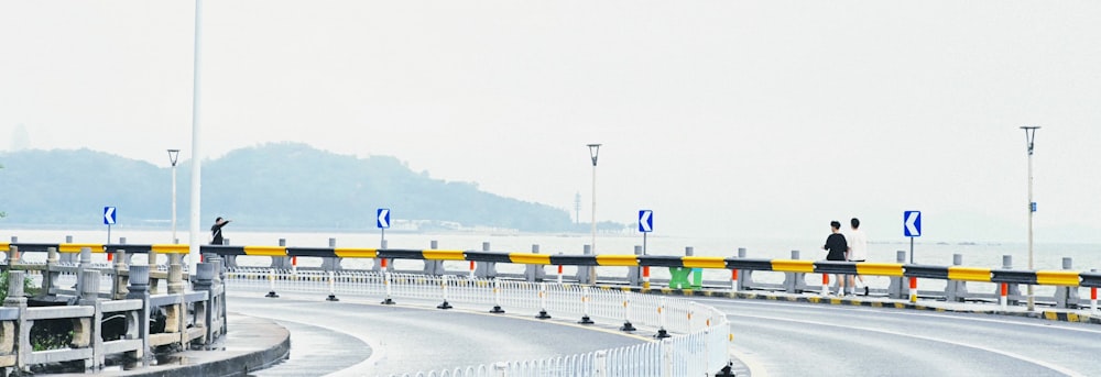 a couple of people standing on a bridge over a road