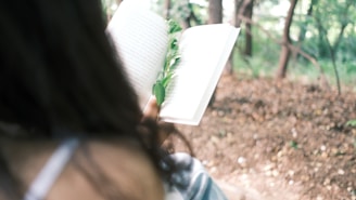 A person reading a guidebook in a peaceful outdoor setting.